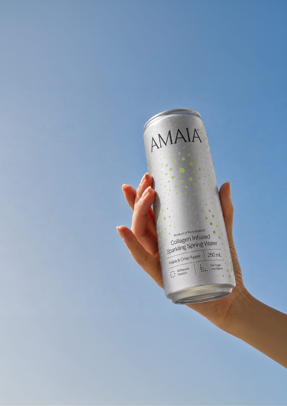 Hand holding an Amaia Feijoa & Crisp Apple can up against a clear blue sky