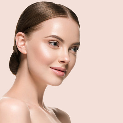 Profile of a woman with her hair in a low bun against a soft pink background